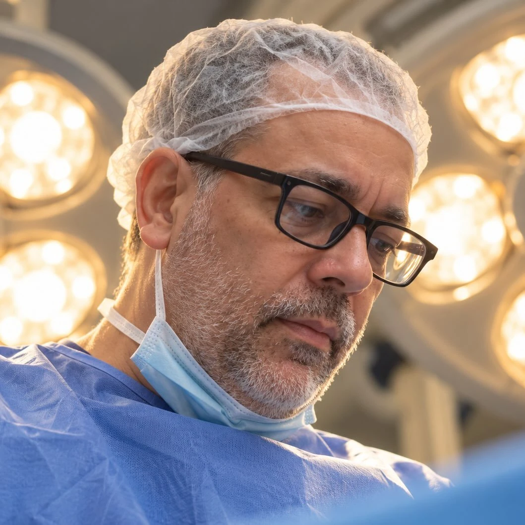 Dr. Frederico Novelino em centro cirúrgico, com touca e óculos